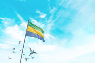 Gabon flag waving with flying doves in beautiful sky. Gabon flag for Republic Day and Independence...