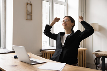 Happy business woman celebrates professional success at workplace with laptop, received positive feedback, recognition from her boss, get promotion or job offer, closed business deal or partnership
