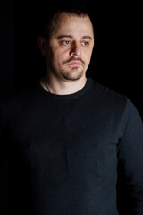 Introspective Man in a Black Sweater Against a Dark Background