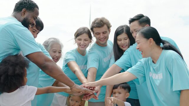 Group of volunteers stand to put your hands up and raise your hands together for help to save nature collecting garbage, people of different ages, Natural environment, pollution concept, wind turbine