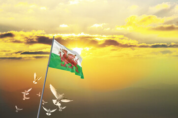 Wales flag waving with flying doves against sunset or sunrise. Wales flag for Republic Day and...