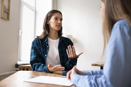 Woman provide helpful information to client or colleague at meeting in office, sit at desk lead conversation, discussing joint project. Applicant pass job interview, answer questions looks confident