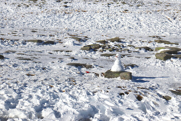 A snowman on a rock in a snow-covered terrain