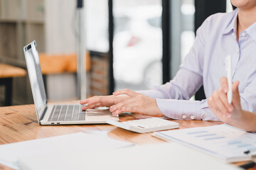 Efficient workspace with laptop, calculator, and documents. person is engaged in work, showcasing productivity and focus in modern office setting