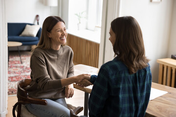 Two young attractive businesswomen, colleagues, client and manager finish meeting in office,...