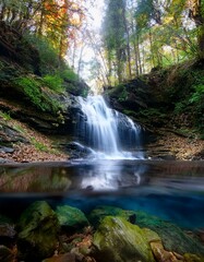 Obraz premium Cascada en medio de un bosque frondos, vista a ras de a cascada