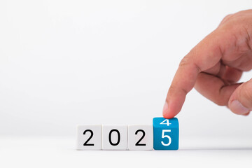 A hand adjusting a calendar cube display to the year 2025, symbolizing time, growth, and future planning.