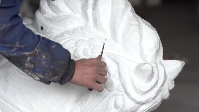 Sculptor's hands straightening and shaving a styrofoam statue. (Taken with 4k custom settings and light)