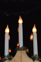 Candles are burning in front of a window glass.