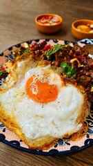 Close up Thai fried egg with spicy stir fried braised beef tendon basil in dish on wooden background and blurred sauce. Special meal and Famous food in Thailand. Selective focus.