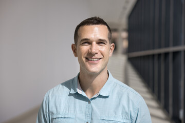 Positive confident Caucasian businessman posing in office corridor for head shot. Entrepreneur,...