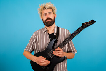 Obraz premium Guy plays blues on white . music male man concept. guy standing with a guitar on blue . a guy with a blue guitar and a musician standing in lifestyle the.