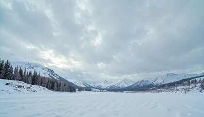 Naklejka premium Expansive winter landscape featuring a snowy lake and mountains under a cloudy sky
