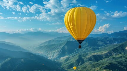 Fototapeta premium Yellow hot air balloon is floating in the air above scenic mountains on sunny day. Ballooning in mountains, recreational adventure