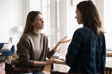 Young woman provides information, giving professional advice to pretty female colleague during...