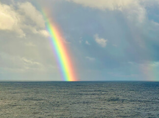 Brilliant rainbow appears after a thunderstorm over the Caribbean Sea glowing like a beacon of bright colourful light