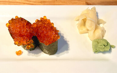 Delicious Japanese Ikura salmon roe caviar sushi with pickled ginger and hot spicy wasabi reddish paste