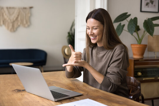 Young woman interacting remotely using laptop, video call application and hand gestures, teaching learner, show symbols, take part in distancing lesson of sign language. Online therapy, communication