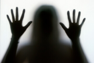 Silhouette of a woman behind the glass. Woman showing gesture stop. Stop violence and sexual abuse...