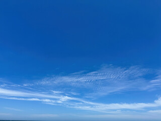 Fototapeta premium Clear blue sky with light, white clouds background. Expansive blue sky and thin scattered clouds