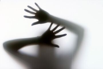 Silhouette of a woman behind the glass. Woman showing gesture stop. Stop violence and sexual abuse against women. Melancholy and crisis concept.
