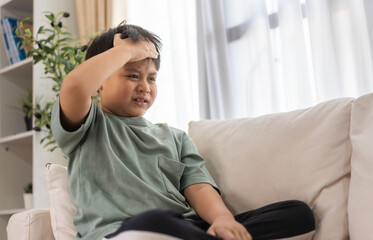 Sick asian child with headache wrapped in blanket, feeling unwell and uncomfortable, young boy experiencing illness symptoms, home healthcare and fever relief, childhood cold or flu recovery