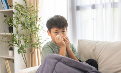 Young asian boy sneezing or blowing his nose and mouth with tissue, cold allergies or illness, health, virus and flu season, RSV, Influenza, childcare and hygiene practices, especially for children