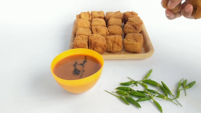 Hand holding fried tofu or sumedang tofu which is a favorite food on a white background