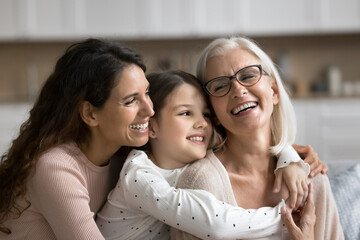 Three generational women embracing, smiling spending pleasant time together, celebrate life event, Happy Mother Day at home, close up. Family unity, love, deep connection between different generations