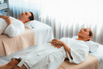 Obraz premium Caucasian couple customer enjoying relaxing anti-stress spa massage and pampering with beauty skin recreation leisure in day light ambient salon spa at luxury resort or hotel. Quiescent