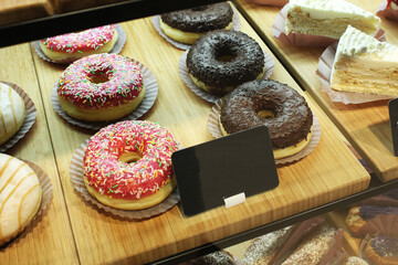 Donuts cakes in pink chocolate glaze with colored sprinkles in the cafe window. Sale of traditional...