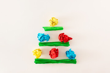 Christmas tree made of colorful papers on a white background. Abstract idea of Christmas tree. Happy winter holiday concept