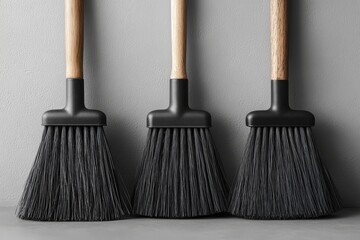 Three black brooms on a gray background. Cleaning, clean house, sweep, wash
