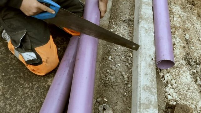 Cutting grey telecom ducts for new internet cable with hand saw