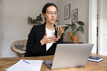 Young businesswoman hold smartphone using speaker function lead formal conversation at workplace...