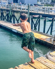 boy jumping into ocean from pier