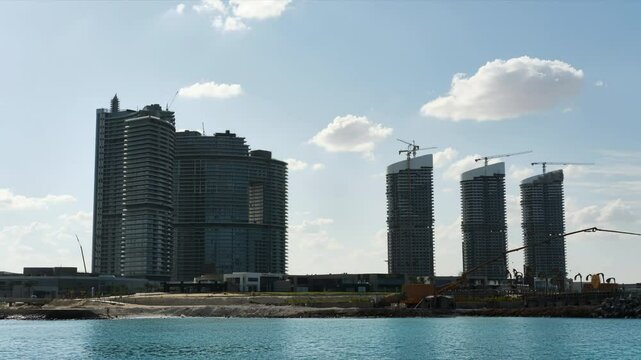 High rise office buildings under construction and clouds passing by at daytime. Skyscrapers timelapse. Tall corporate buildings at New Alamein, Marsa Matrouh governorate, Egypt
