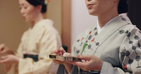 Japan woman, sweet and eating in home for tea ceremony, tradition and cultural ritual with friend. Asian people, kimono and wagashi in house for harmony, respect and heritage honor in Kyoto community