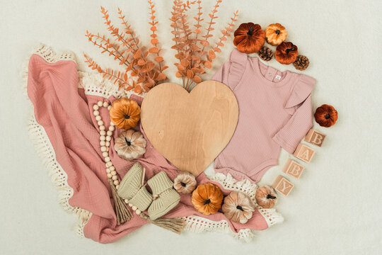 A cozy flat lay featuring a baby bodysuit, pumpkins, leaves, and rustic fall decor. Perfect for pregnancy announcements, autumn themes, and family designs.