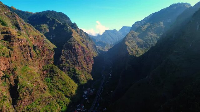 City infrastructure among the high mountains. Aerial perspective on the highway crossing the inhabited area in Madeira, Portugal.