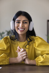 Positive successful Indian freelance blogger girl in wireless headphone vertical head shot....