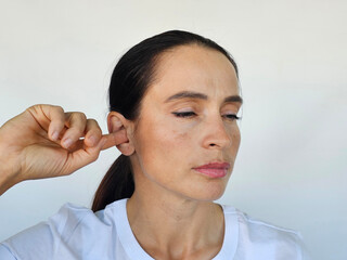 Woman scratches ear with index finger to relieve itch