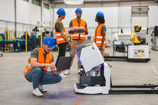 Engineers maintaining automated guided vehicle in modern factory
