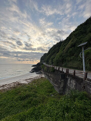 Scenic Coastal Road With Lush Green Cliffside at Sunset