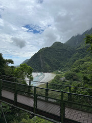 Scenic View of Lush Green Mountains and River Under Cloudy Sky