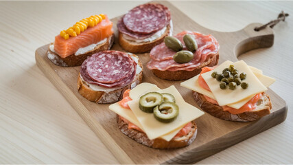Toasted Bread Delights: Slices of toasted bread topped with salmon and corn, salami, cheese with olives, salmon with cheese, and cheese with capers, on a wooden cutting board.