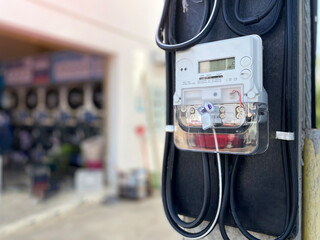 A digital electricity meter on a pole in front of a building is an electronic energy measurement device. It is designed to automatically record water and electricity usage.