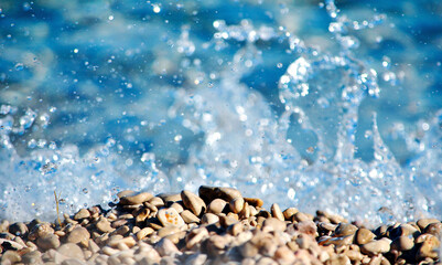 Detail of a Wave Breaking on Pebbles: Focus on Beach Details. details of water drops in suspension.