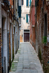 Obraz premium a view into a deserted narrow alley in Venice with dilapidated walls