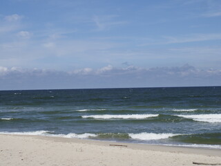 Serene beach landscape with waves and blue sky on the horizon